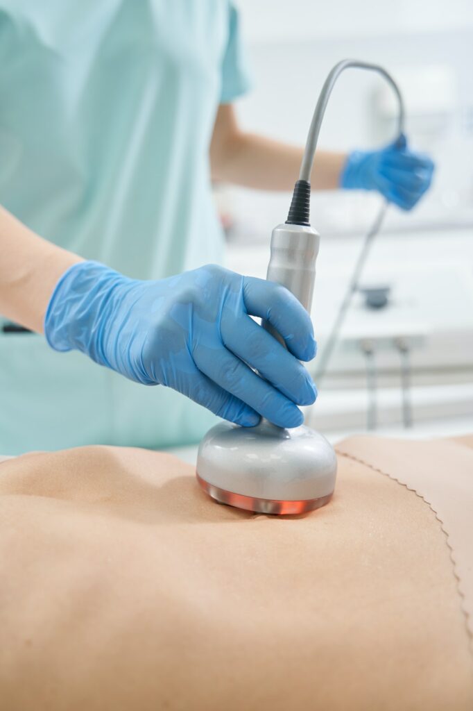 Hand holding radiofrequency beauty gadget on stomach