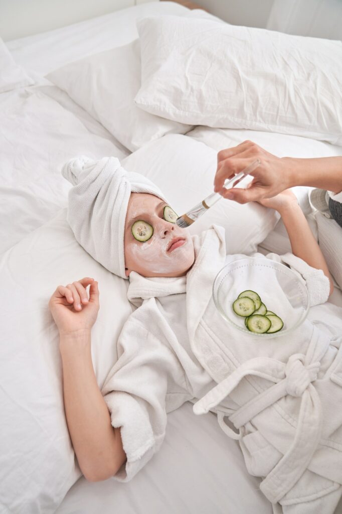 Unrecognizable woman applying facial mask on child
